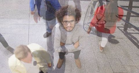 Man in Urban Setting Looking Upward with People Passing By