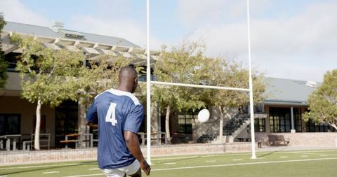 Athlete Kicking Rugby Ball on Outdoor Field Toward Goal Post