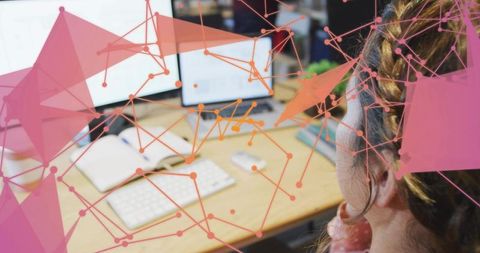 Woman focusing at dual-monitor workstation with network overlay visualizing data flows