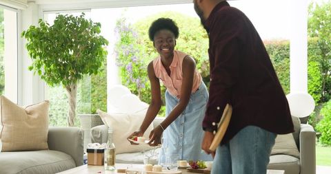 Couple setting table for lunch in modern living room