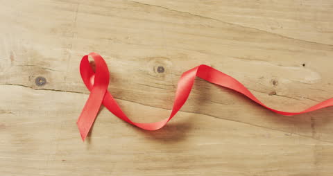 Red Awareness Ribbon on Wooden Surface Symbolizing Support