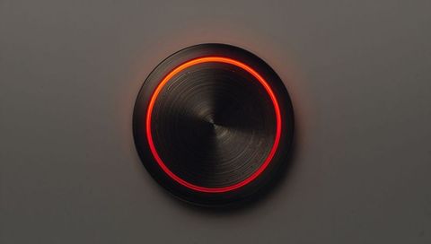 Glowing brushed metal knob with red-orange led ring casting halo on light-gray panel