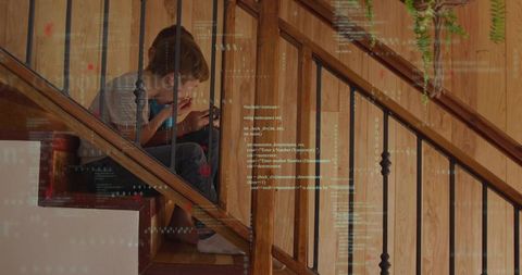 Siblings using tablet on wooden staircase with code overlay conveying digital learning