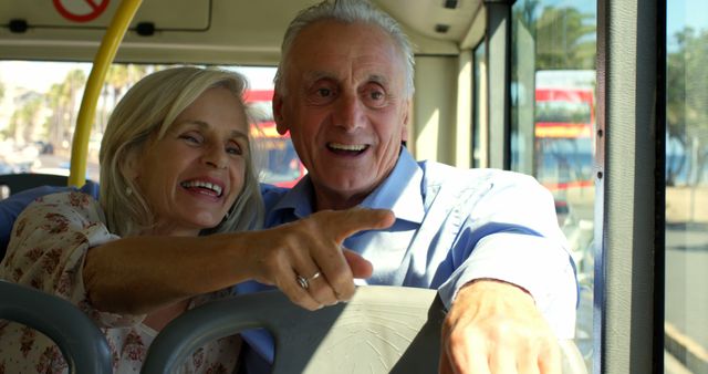 Happy senior caucasian couple sitting in city bus looking through window. Transport, city living and senior lifestyle, unaltered.
