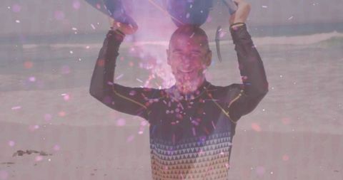 Smiling man lifting foam boards with sparkling confetti on beach