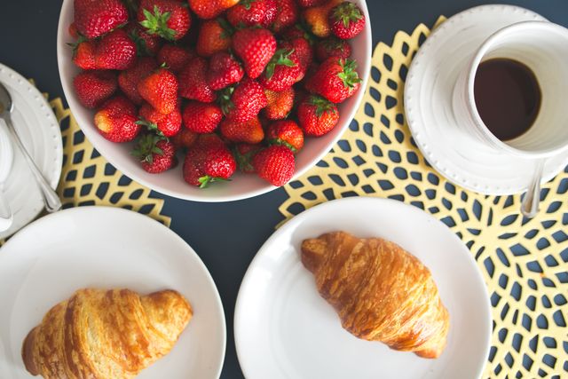 Fresh buttery croissants, hot cup of coffee and bowl with strawberries - Download Free Stock Photos Pikwizard.com