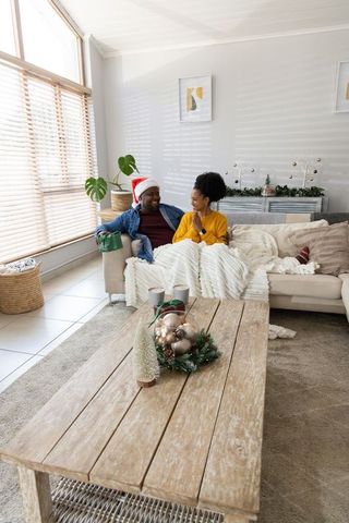 African american couple sharing cozy holiday moment on couch with gift and santa hat