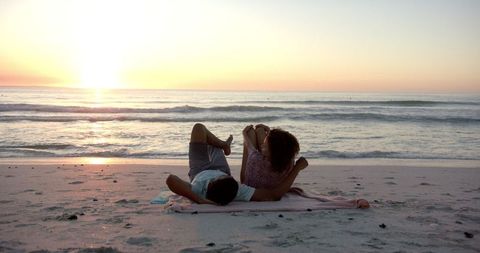 Couple Relaxing on Beach at Sunset with Calm Waves - Download Free Stock Images Pikwizard.com