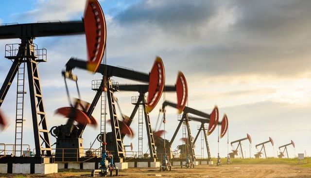 Pumpjacks pumping oil at golden hour with red counterweights on dry concrete pads