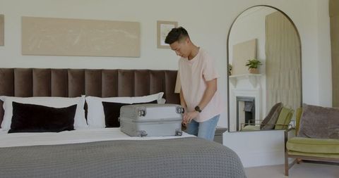 Man Packing Suitcase with Laptop in Bright, Modern Interior