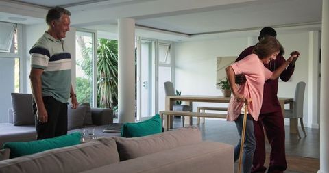 Senior woman walking with cane and assistance, home support atmosphere