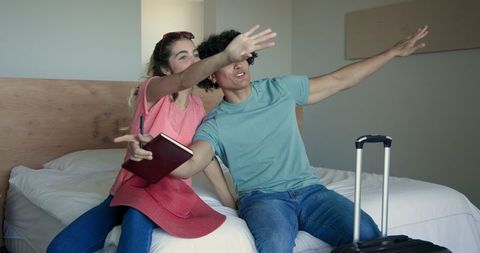 Young couple organizing for travel adventure on bed with suitcase