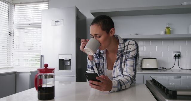 Woman Enjoying Coffee and Browsing Smartphone in Modern Kitchen - Download Free Stock Images Pikwizard.com