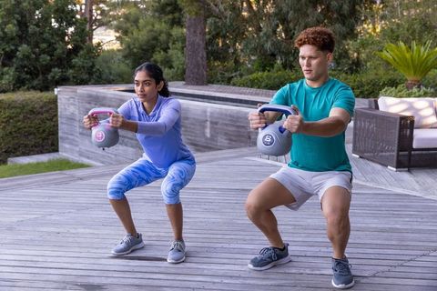 Friends exercising with kettlebells on outdoor deck