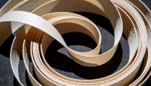 Curled wood veneer strips forming spiral loops and strong shadow patterns macro texture