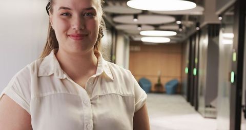 Confident Woman in Modern Office Hallway with Glass Doors