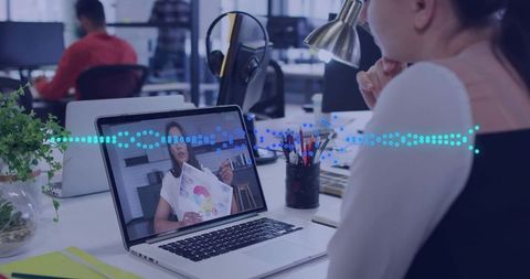 Woman watching virtual presentation on laptop in open office for remote collaboration