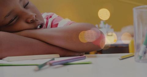 Tired schoolchild sleeping on desk during classroom lesson with pencils and markers