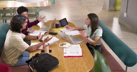 African American coworkers collaborating at modern coworking table with laptops and notes
