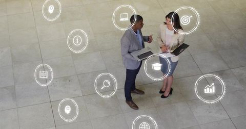 Business Professionals Collaborating in Atrium with Floating Digital Icons for Analytics