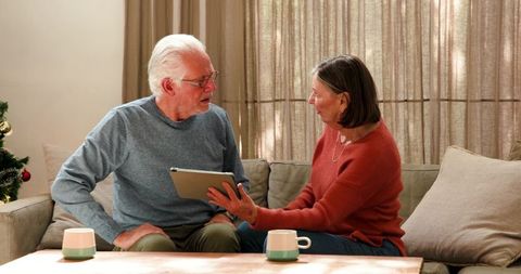 Senior couple enjoying tablet time in living room during holidays