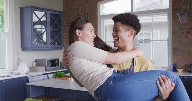 Happy biracial couple embracing and laughing together in kitchen. quality time, relaxing together at home.