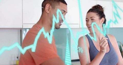 Young couple interacting with holographic financial data graph in modern home kitchen