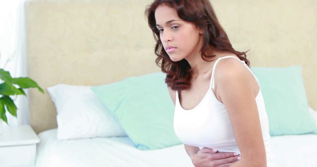 Young Woman Suffering Abdominal Pain in Bedroom - Download Free Stock Images Pikwizard.com