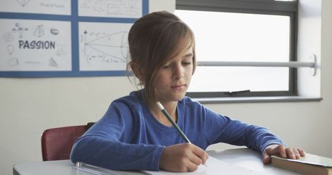 Boy Concentrating While Writing in Classroom - Download Free Stock Images Pikwizard.com