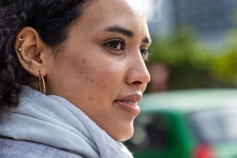 Closeup profile of woman wearing scarf and hoop earring, urban daylight portrait