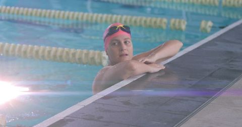 Female Swimmer Resting at Pool Edge Wearing Pink Cap and Goggles During Training Break