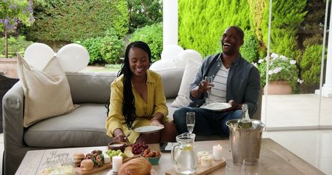 Joyful Couple Enjoying Champagne on Patio with Outdoor Snack Spread