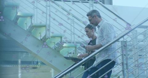 Professionals Discussing Digital Project on Modern Atrium Stairs