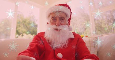 Festive Senior Man in Santa Costume Enjoying Video Call at Home