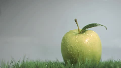 Fresh Green Apple and Dewdrops on Grass with Grey Background