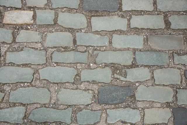 This image shows a close-up view of a cobblestone pavement, highlighting the texture and pattern of the stones. It can be used for backgrounds, architectural designs, urban planning presentations, or historical context illustrations.