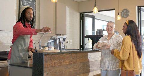 Barista serving cupcakes and coffees to diverse customers in cozy rustic cafe interior