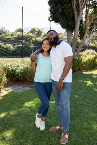 Happy couple embraces outdoors by tennis court on sunny day
