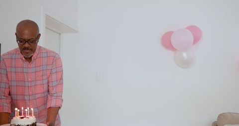 Senior Man Presenting Birthday Cake at Cozy Home Gathering