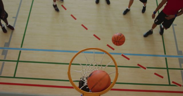 Overhead view of african american male basketball player scoring goal against diverse players. basketball, sports training at an indoor court.