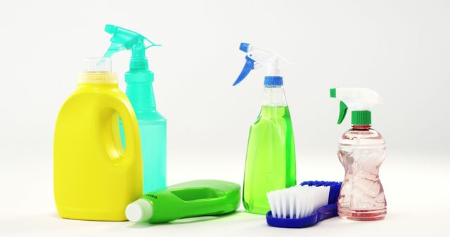 Various household cleaning products and tools including spray bottles, detergent, and a cleaning brush are arranged on a white background. This can be used in contexts related to hygiene, cleaning services, domestic cleaning tips, or advertisements for cleaning supplies.