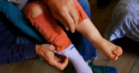 Father Assisting Son with Socks at Home in Cozy Bedroom