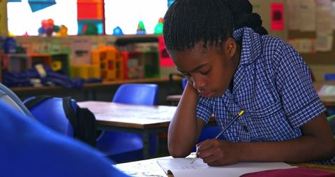 Focused Schoolgirl Diligently Writing in Classroom Setting - Download Free Stock Images Pikwizard.com