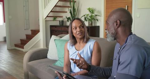 African american woman discussing health care plan with male nurse during home visit