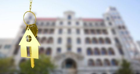 Gold key with house charm symbolizing home ownership