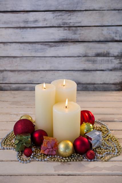 Warm and inviting Christmas scene with lit candles surrounded by festive ornaments and beads. Ideal for holiday greeting cards, seasonal marketing materials, and festive interior design inspiration.