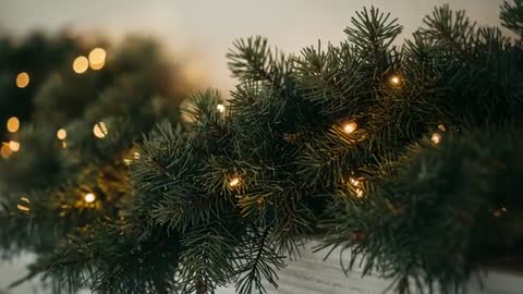 Camera closing in on evergreen garland needles glowing with warm white lights on painted mantel