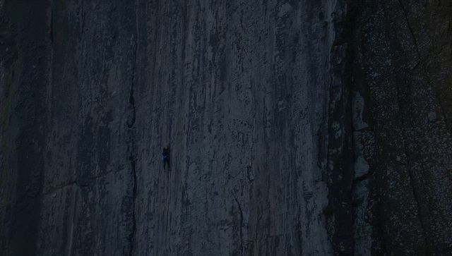 Solo climber scaling granite cliff at twilight, rope harness and helmet, moody vertical adventure