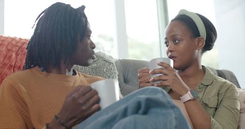 Cozy African American Couple Sharing Coffee on Couch, Intimate Conversation at Home
