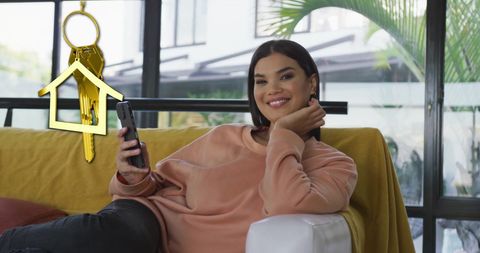 Happy Woman Relaxing at Home with Mobile and House Key Symbol